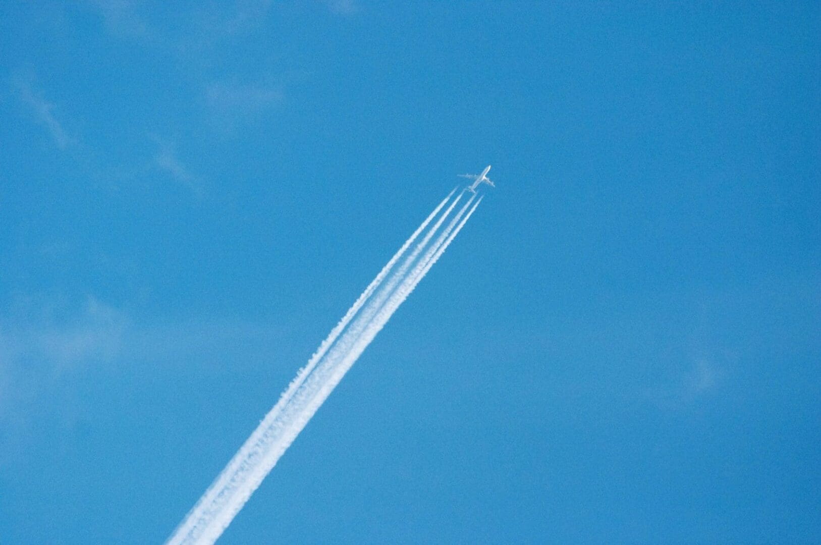 A plane flying in the sky with its tail trailing behind.